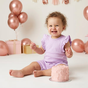 A baby girl is weared a palm and pale purple color romper t to repesent the premium quality of coton fabric for summer weather for newborn baby to 24 months baby girl.