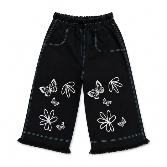 Girls' black wide leg denim pants with white butterfly and floral outline print, teal contrast stitching, elastic waist, and frayed hem — front view