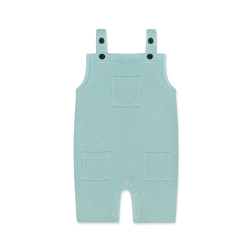 A pastel blue newborn romper with button-on-shoulder straps and front pockets, displayed against a light background with orange and green design elements. The text highlights features like 'Button on Shoulder,' 'Pockets,' and 'New Arrivals.' The brand name 'Palm and Pale' and website 'palmandpale.com' are also visible. The tagline reads 'Sunny styles for little smiles.'
