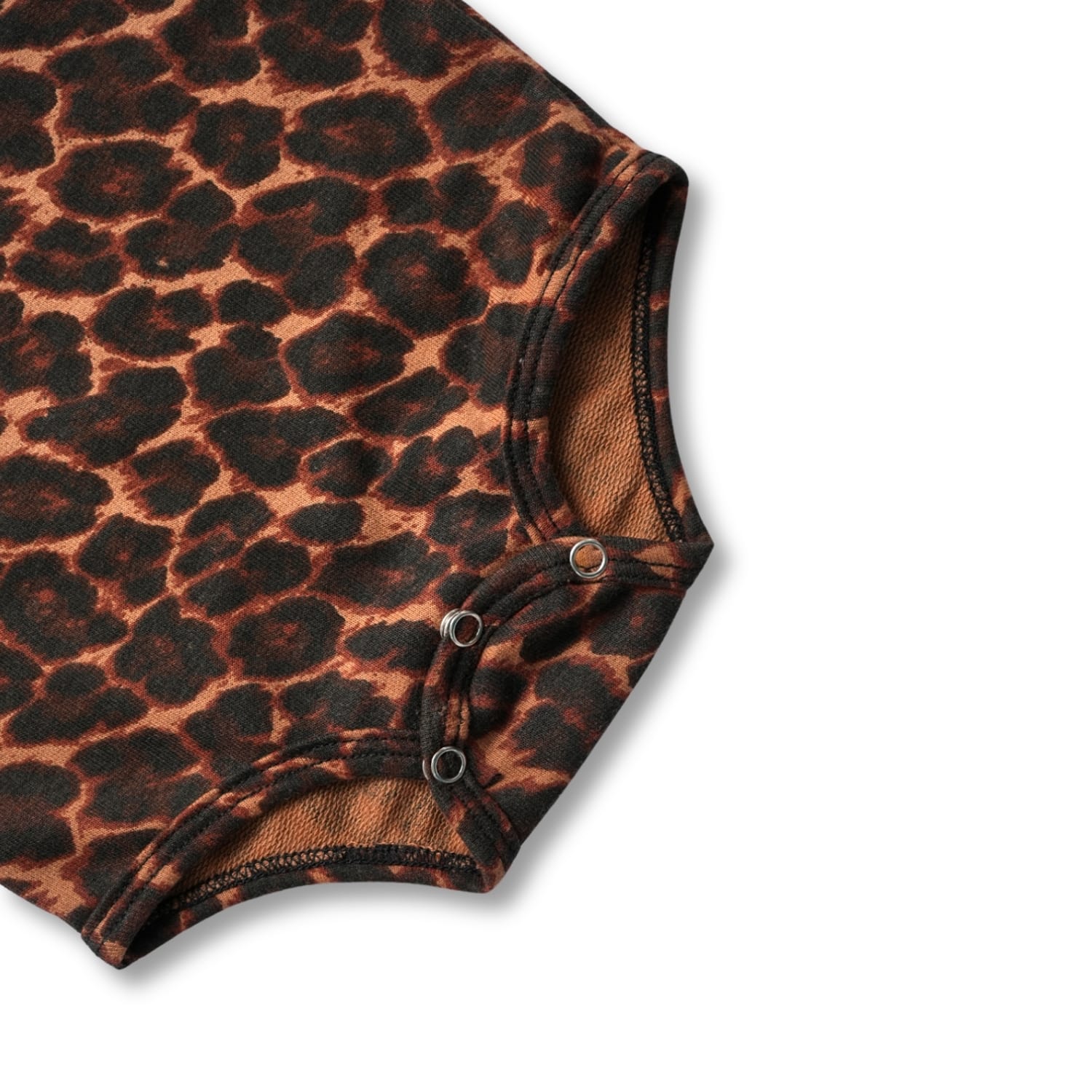Texture close-up of the cotton fabric and snap fasteners on a long-sleeve leopard print infant bodysuit