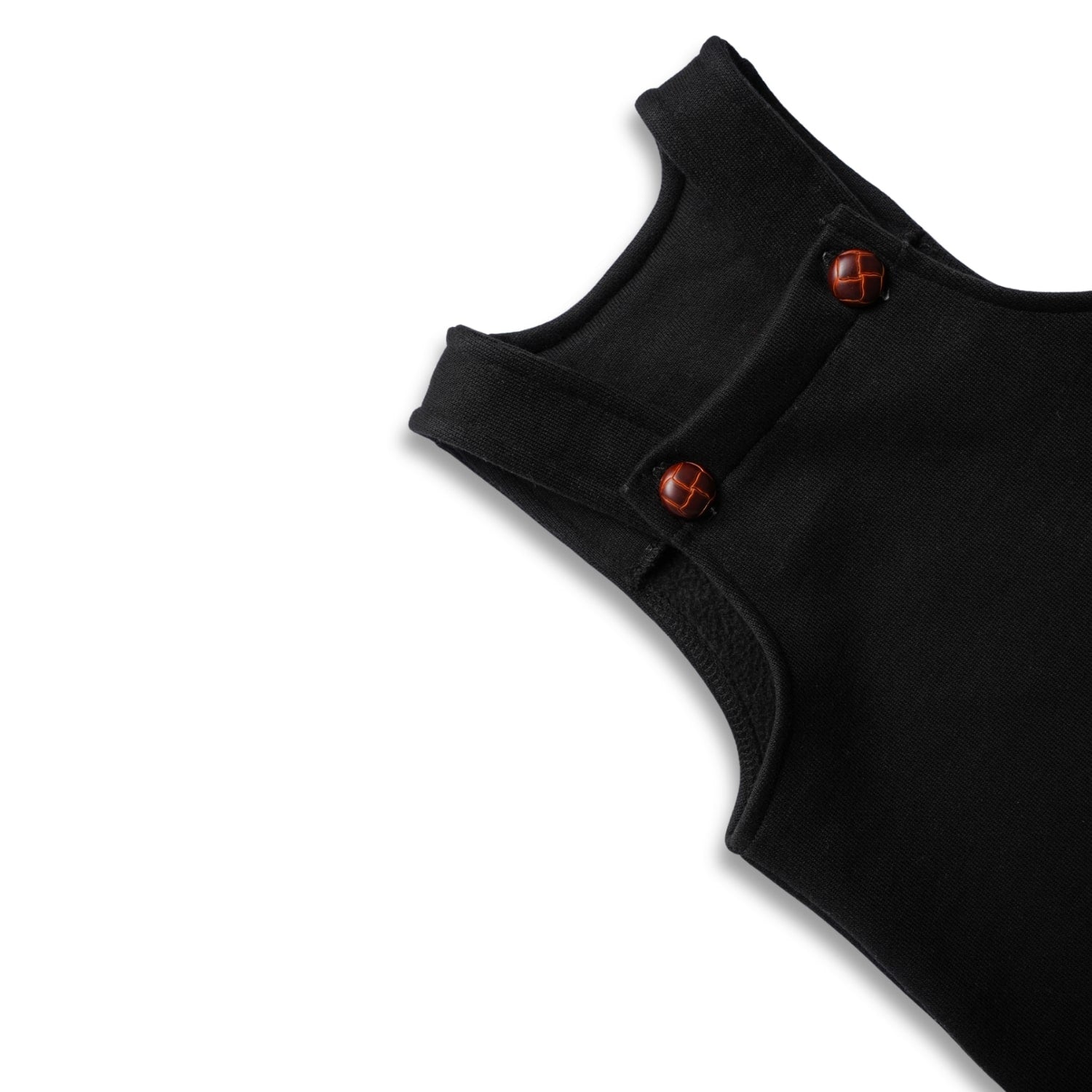 Close-up of the shoulder strap and dark wooden buttons on black baby overalls