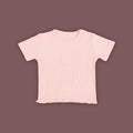 A baby short-sleeved T-shirt in a soft pastel pink color, displayed against a muted brown background. The T-shirt is made from ribbed fabric and features snap buttons on one shoulder for easy dressing. The hem has a subtle wavy finish, adding a delicate touch to the design.