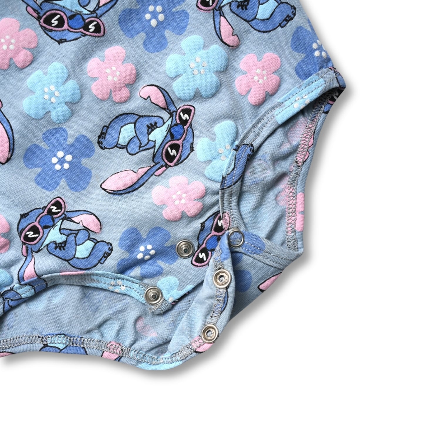 Children's onesie bodysuit with cartoon character and floral pattern on a light blue background